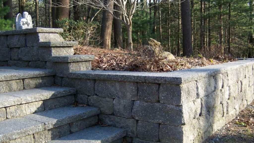 Granite retaining wall with built-in steps in wooded residential landscape