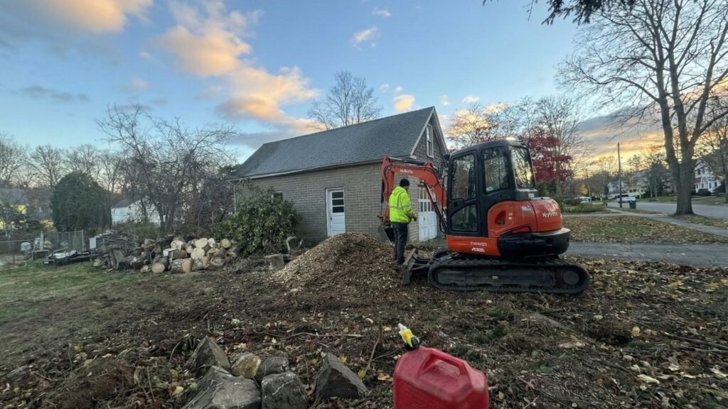 Compact excavator spreading wood chips during residential tree removal cleanup in Seymour Connecticut