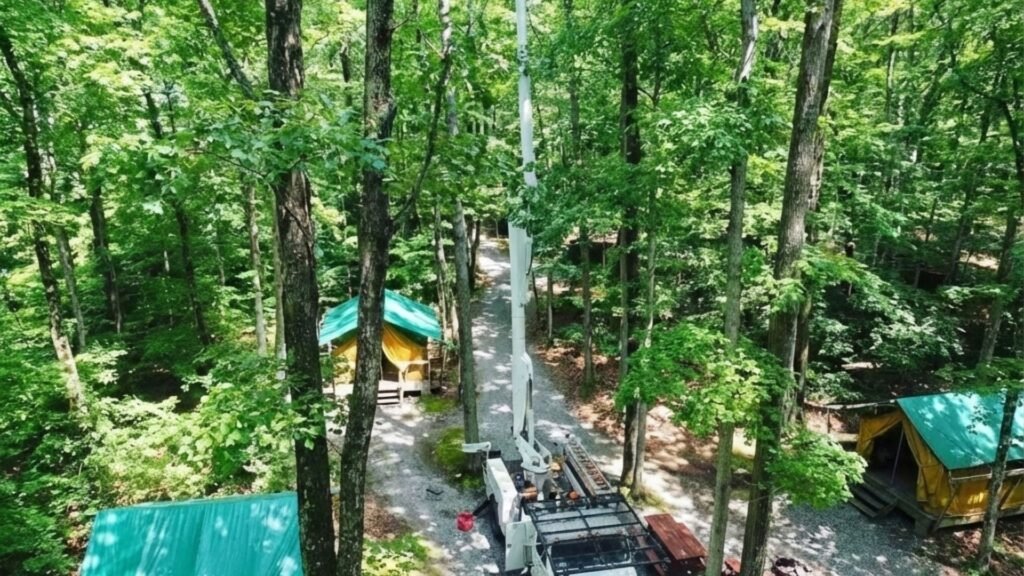 Aerial view of bucket truck extended high among trees at a residential property in Woodbury Connecticut