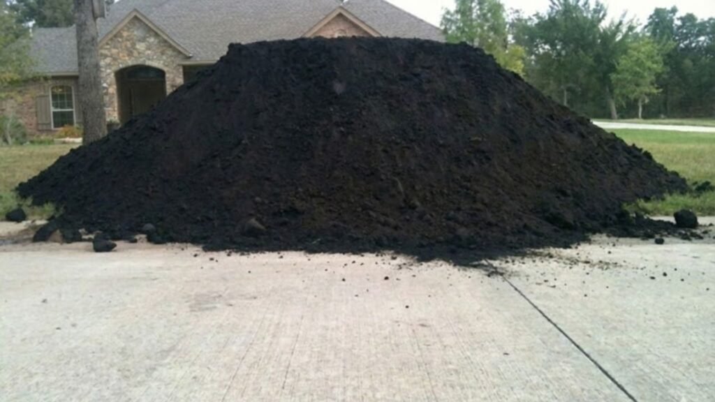 Large Pile of Delivered Topsoil Near Me on Concrete Driveway