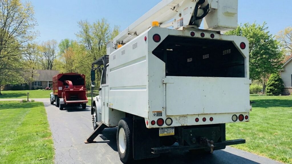 Rear view of bucket truck and wood chipper lined up on a residential driveway in Roxbury Connecticut