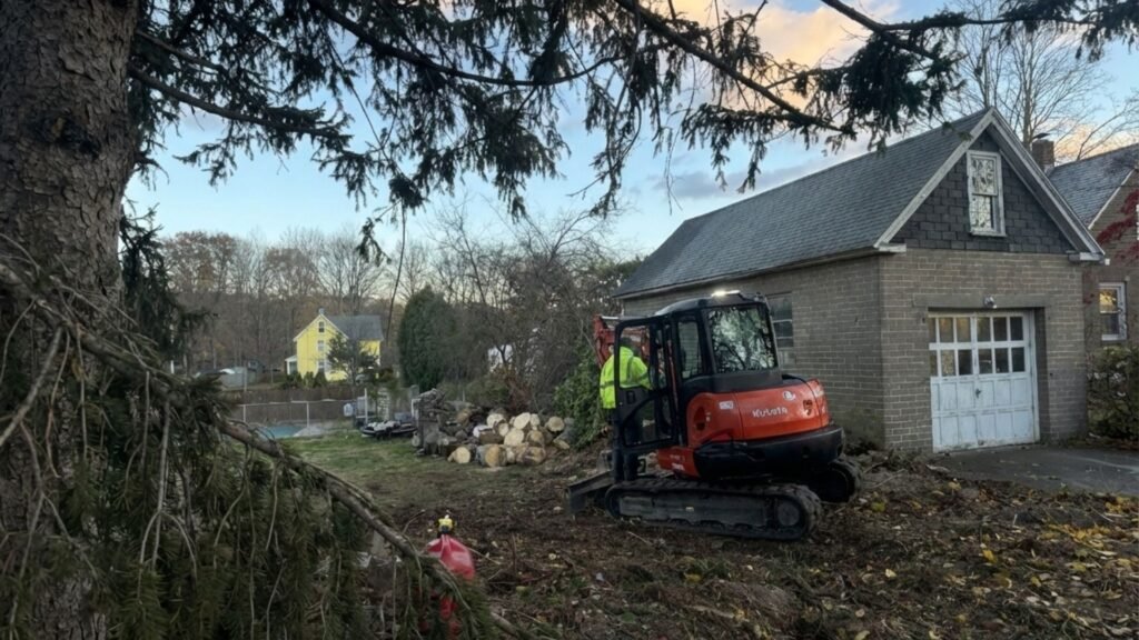 Excavator clearing fallen tree branches during residential tree removal in Seymour Connecticut