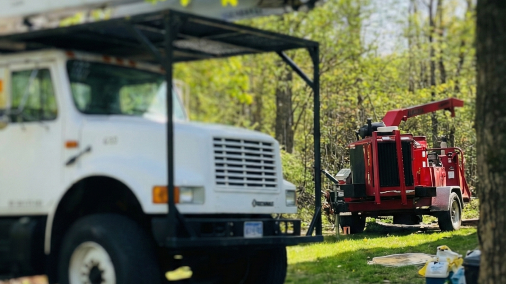Bucket truck and red wood chipper staged on a wooded residential driveway in Roxbury Connecticut