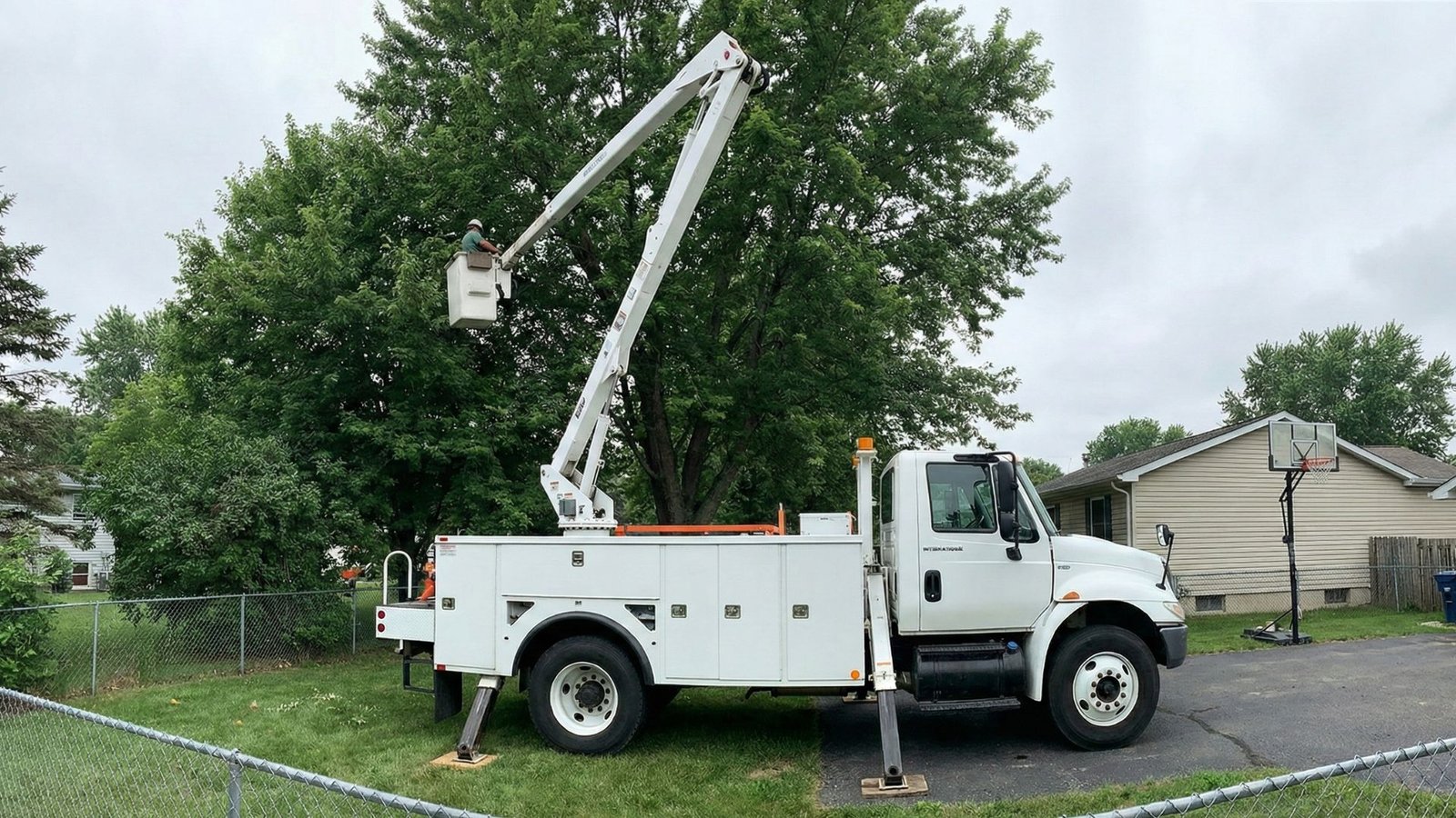 Bucket truck with boom extended over a residential tree during removal work in Woodbridge Connecticut