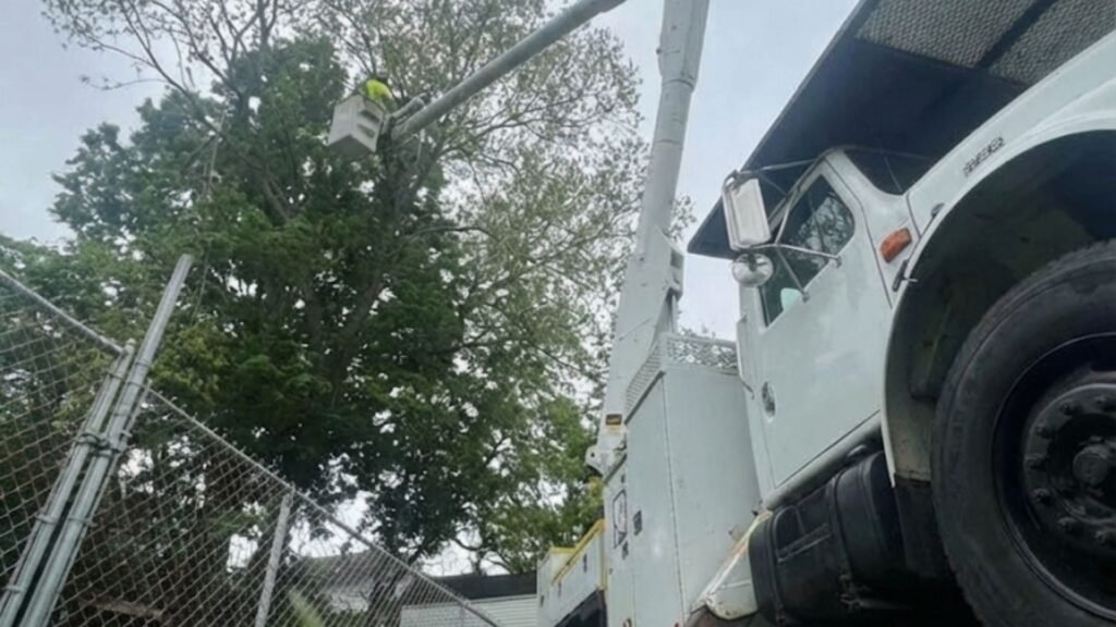 Trusted tree removal crew using stabilized bucket truck near residential fence in Bridgewater Connecticut