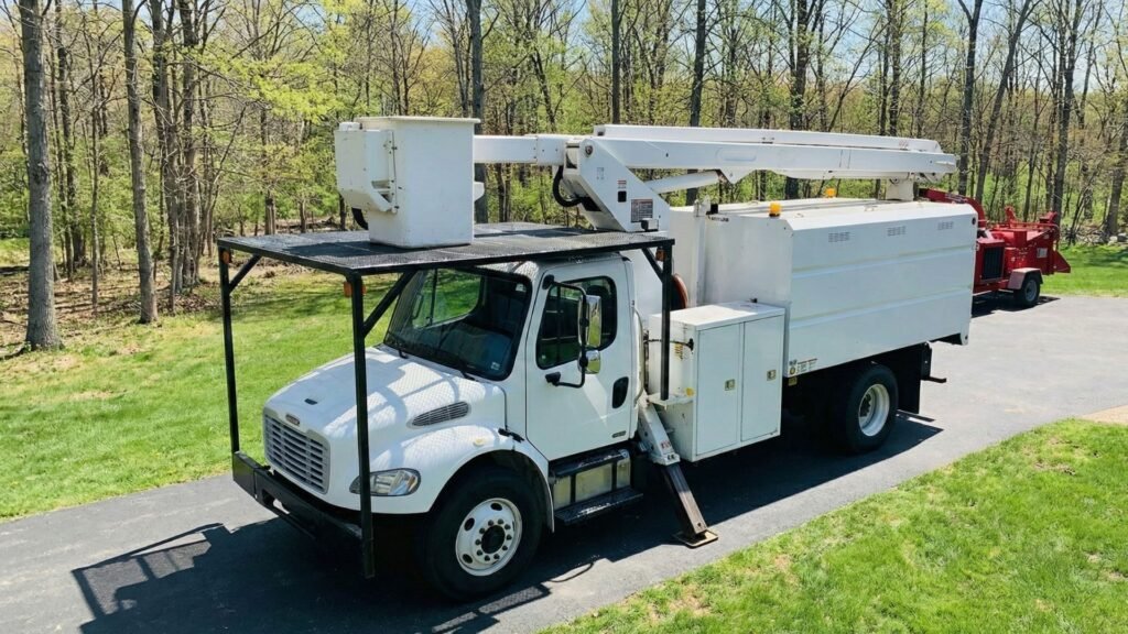 Bucket truck with extended boom positioned on a residential driveway for tree removal in Roxbury Connecticut