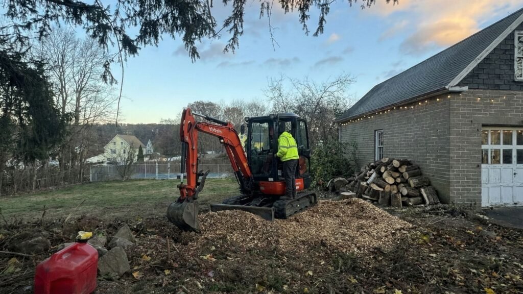 Compact excavator handling wood debris and ground cleanup at a residential property in Seymour Connecticut