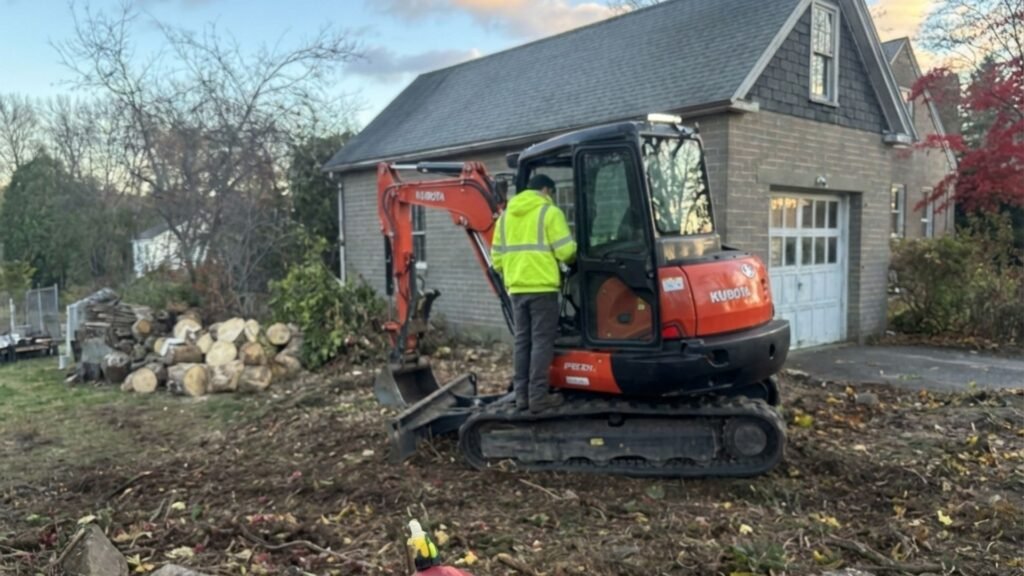 Excavator operator clearing debris during residential tree removal in Seymour Connecticut