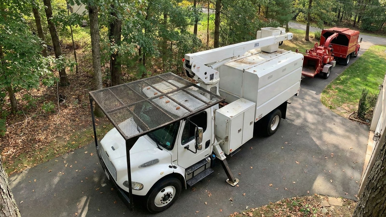Bucket truck and wood chipper staged on a residential driveway during tree removal work in Roxbury Connecticut