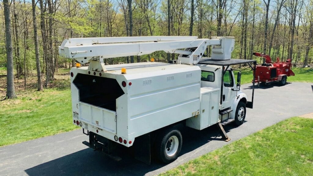 Rear view of bucket truck and wood chipper staged on a residential driveway in Roxbury Connecticut