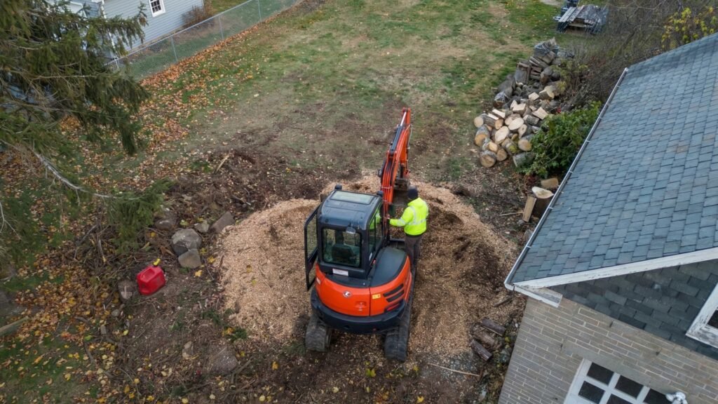 Aerial view of a compact excavator managing wood chips and debris during tree removal in Seymour Connecticut