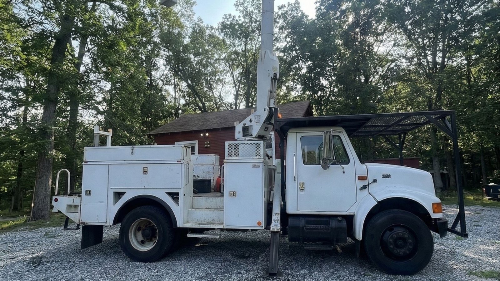 White bucket truck positioned on gravel near a wooded residential area in Prospect Connecticut