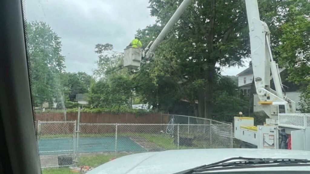 Tree removal technician operating bucket lift over residential yard in Bridgewater Connecticut